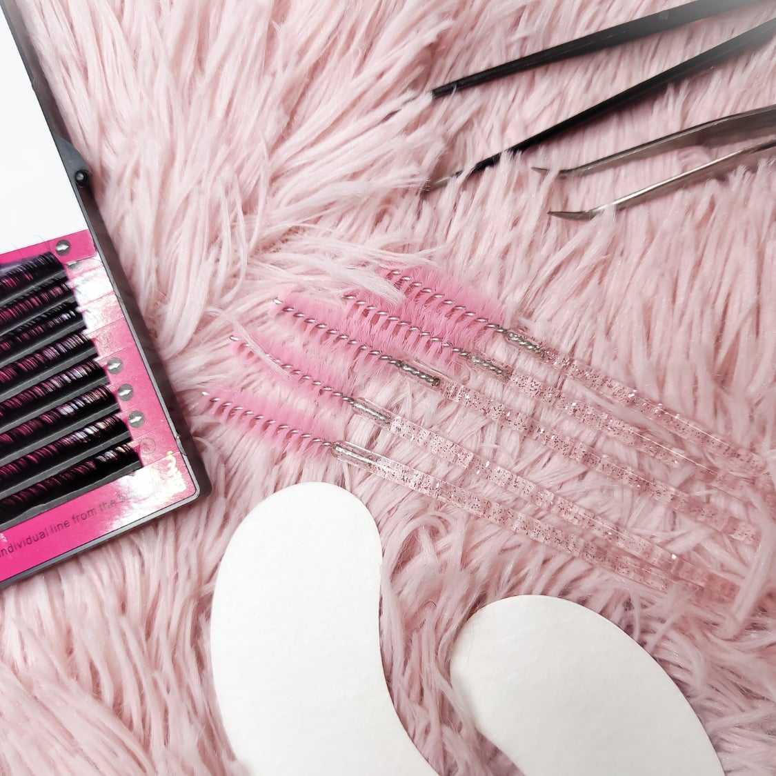 Eyelash extension tools and supplies on a pink furry surface.